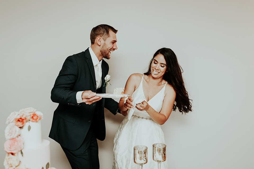 Dragon-point-villa-wedding-bride-and-groom-with-cake-bride-in-a-white-ballgown-with-pockets-and-thin-straps-groom-in-a-black-suit-with-a-white-tie