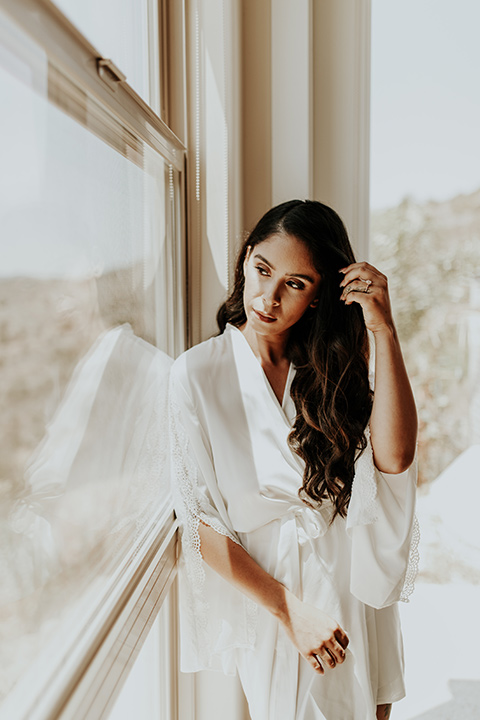 Dragon-point-villa-wedding-bride-looking-out-window-in-a-white-silk-robe