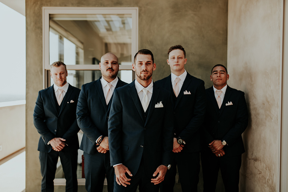 Dragon-point-villa-wedding-groomsmen-in-black-suits-with-light-pink-ties-and-groom-in-a-white-tie