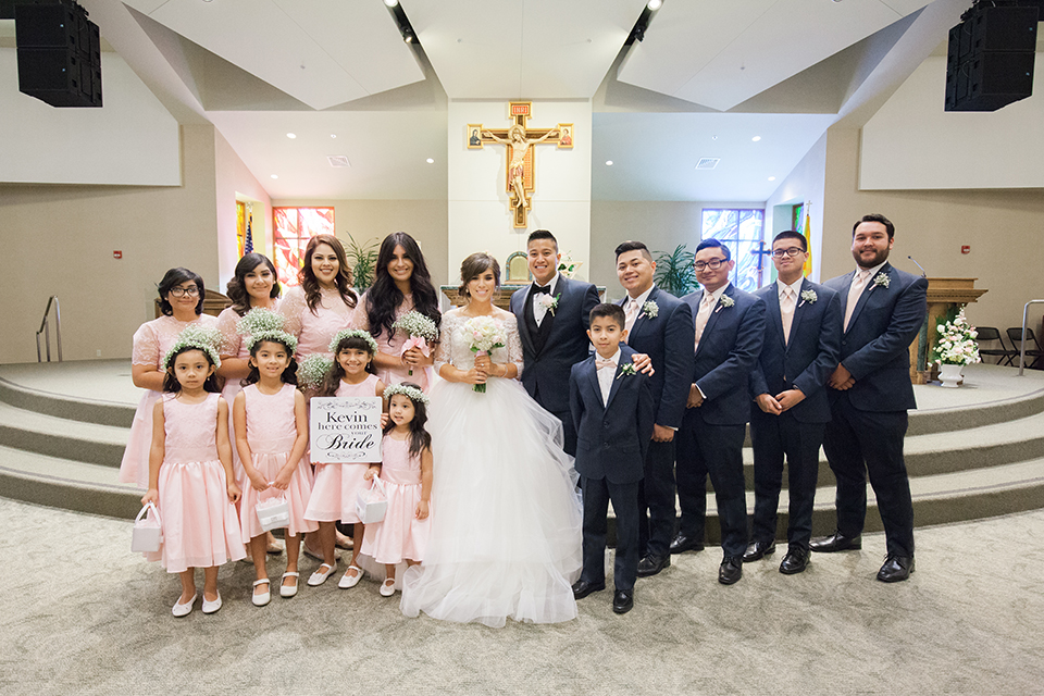 Elements-Venue-presents-wedding-bridal-party-bridesmaids-in-pink-gowns-groomsmen-in-navy-suits-with-pink-long-ties-bride-is-in-a-layered-tulle-ball-gown-with-a-high-neckline-and-quarter-sleeves-groom-in-a-navy-blue-shawl-lapel-tuxedo-with-a-black-bow-tie