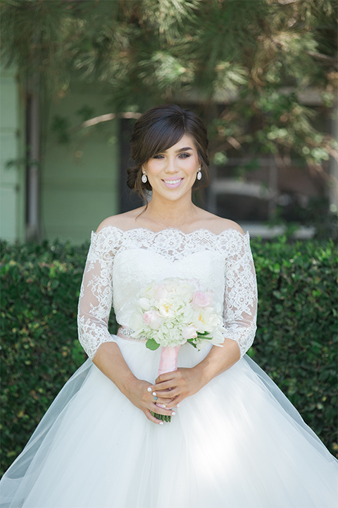 ”Elements-Venue-presents-wedding-bride-and-groom-walking-away-bride-is-in-a-layered-tulle-ball-gown-with-a-high-neckline-and-quarter-sleeves-groom-in-a-navy-blue-shawl-lapel-tuxedo-with-a-black-bow-tie"