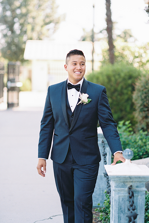 ”Elements-Venue-presents-wedding-groom-walking-in-a-navy-blue-shawl-lapel-tuxedo-with-a-black-bow-tie"