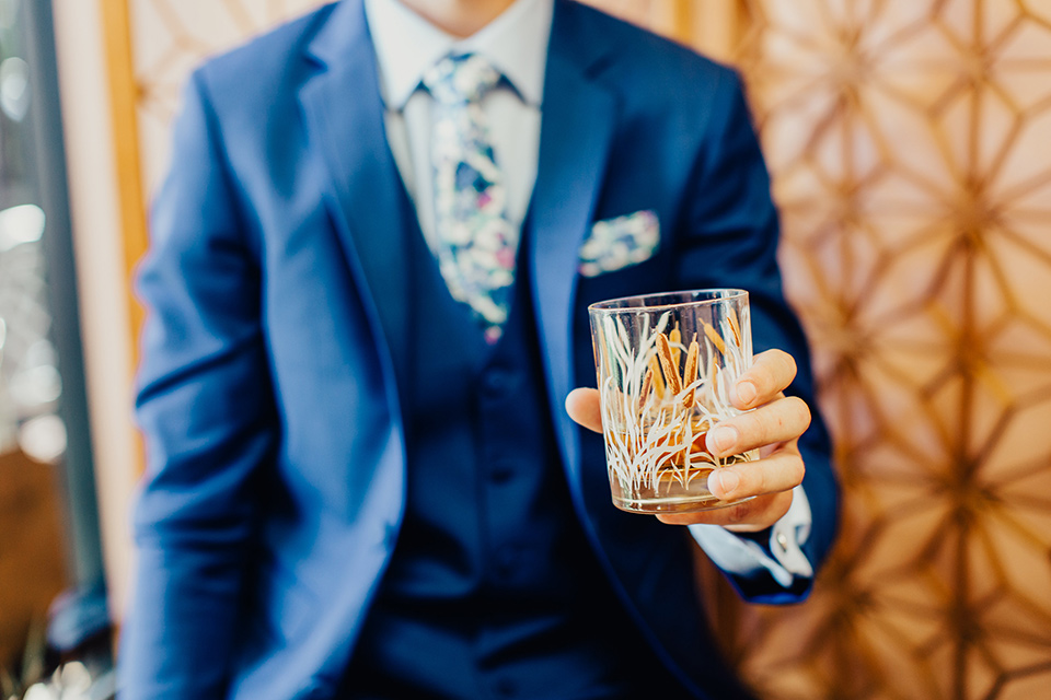 Disco style wedding blue suit up close while holding whiskey glass