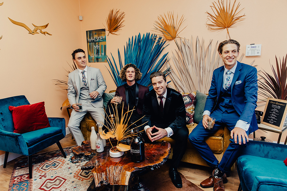 Groom and groomsmen posing for a picture on a couch wearing suits