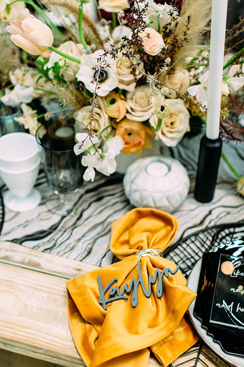 disco style wedding table decor with with deep vintage mustard napkin with a black plate and white candles and florals