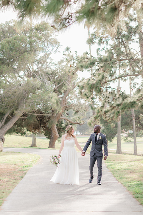 Los-Verdes-Golf-Course-Wedding-bride-and-groom-walking-towards-the-camera-bride-in-a-white-gown-with-cap-sleeves-groom-in-a-charcoal-tuxedo-with-a-black-tie