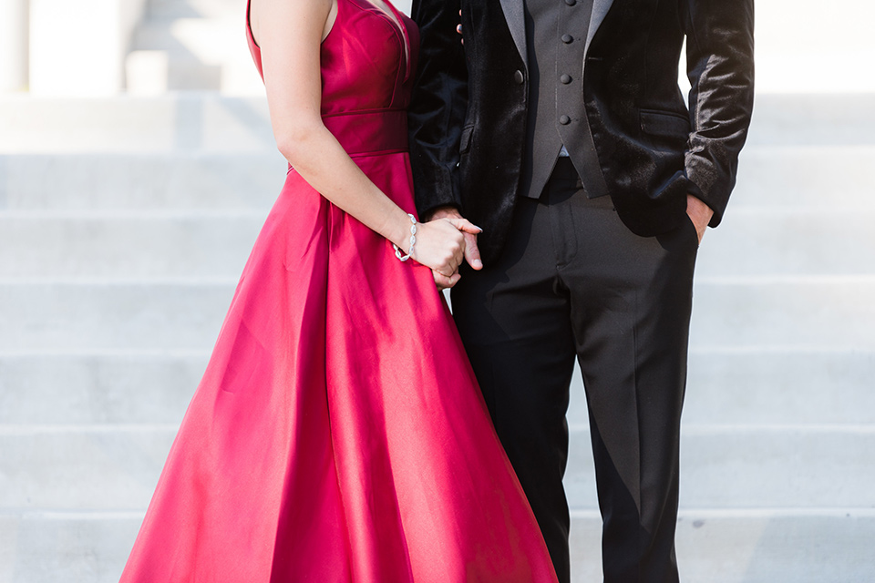  bride in a red evening gown with a plunging neckline and hair in a bun, groom in a black velvet tuxedo and black bow tie 