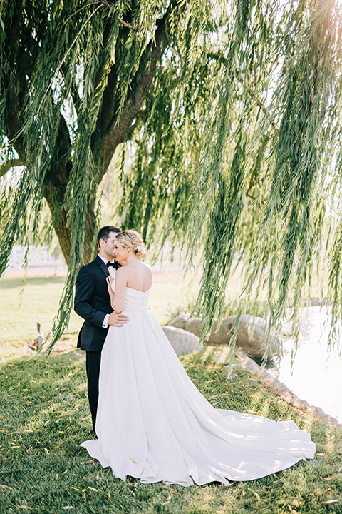 bride and groom willow tree, bride in a white strapless ballgown with a bow detail and hair in a bun, groom in a black tuxedo with a black bow tie