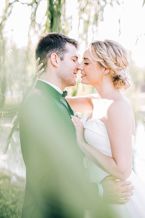  bride in a white strapless ballgown with her hair in a bun, groom in a black tuxedo with a black bow tie 