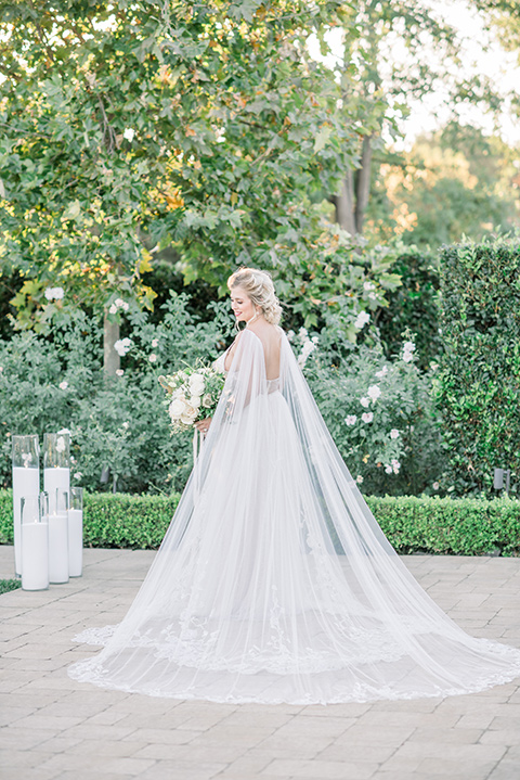 bride in a white gown with a plunging neckline and a sheer cape and train