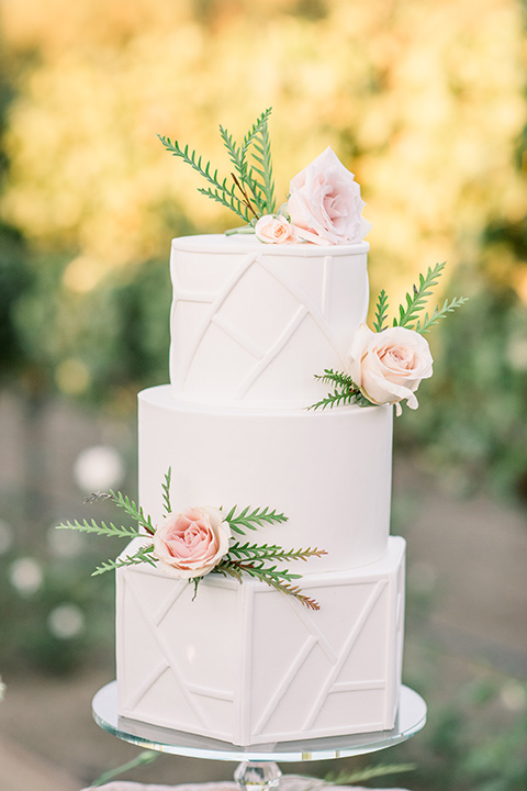 white three-tiered cake with pink floral designs 