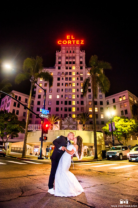 San-Diego-Wedding-bride-and-groom-in-the-street-bride-in-a-white-lace-gown-with-an-off-the-shoulder-neckline-groom-is-in-a-black-tuxedo-with-a-black-bow-tie