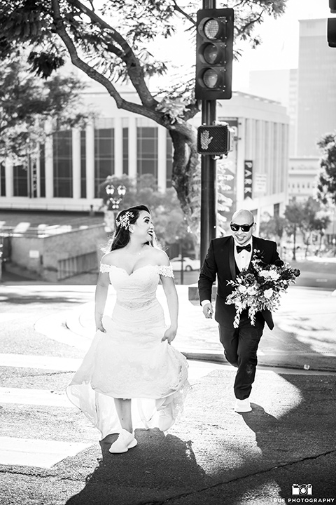 San-Diego-Wedding-bride-and-groom-running-bride-in-a-white-lace-gown-with-an-off-the-shoulder-neckline-groom-is-in-a-black-tuxedo-with-a-black-bow-tie