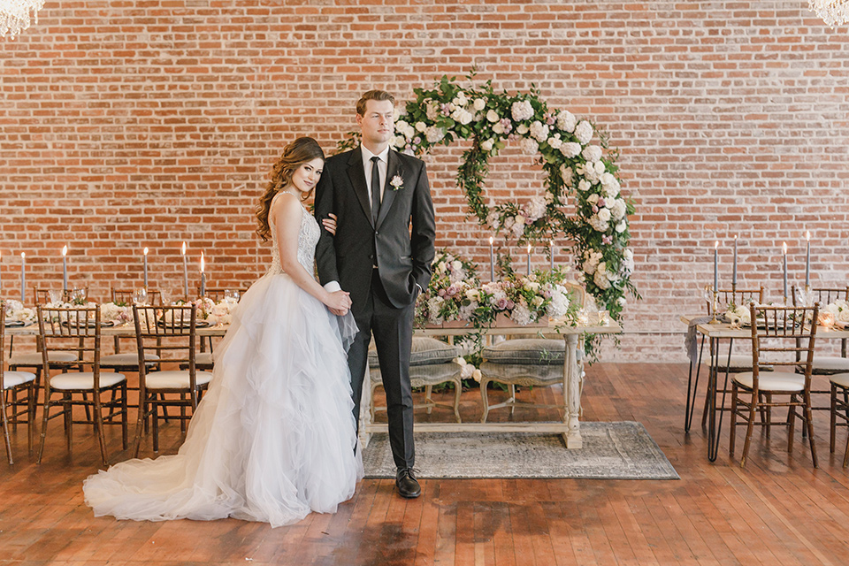 bride in a white tulle ballgown with a low back and a sweetheart neckline and the groom in a black tuxedo with a long black tie