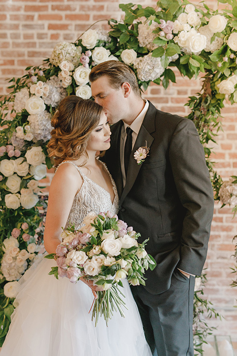 bride in a white tulle ballgown with a low back and a sweetheart neckline and the groom in a black tuxedo with a long black tie