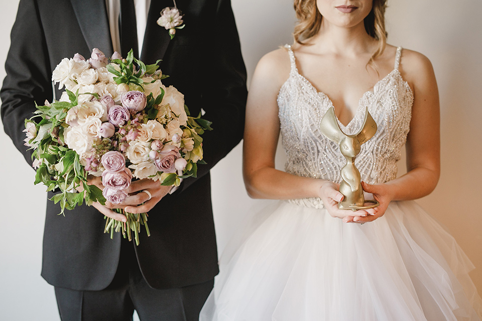 bride in a white tulle ballgown with a low back and a sweetheart neckline and the groom in a black tuxedo with a long black tie