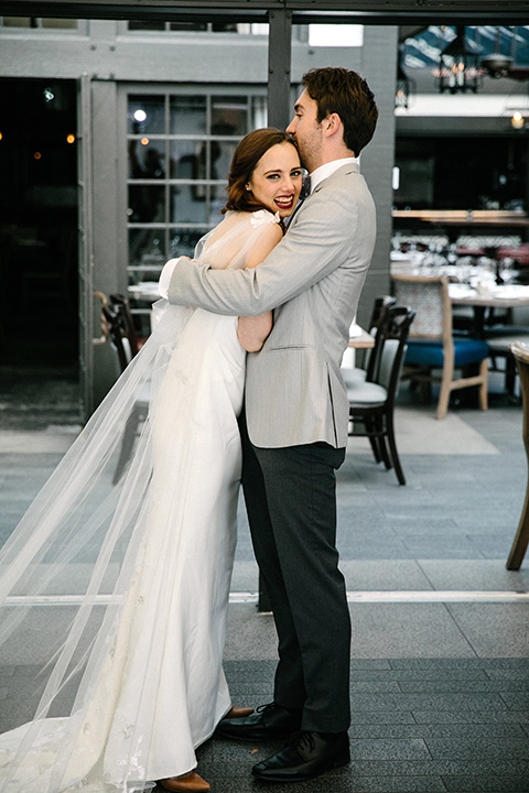 bride in a white flowing gown with cap sleeves and the groom in a grey suit coat with a pair of black pants and a velvet grey bow tie