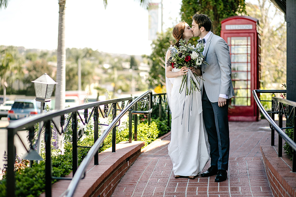 The bride in a white gown with lace long sleeves and a high neckline the groom in a light grey suit with black pants and a grey velvet bow tie