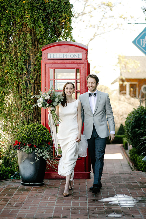 bride in a white lace gown with cap sleeves and a light grey suit coat and black pants with a grey velvet bow tie