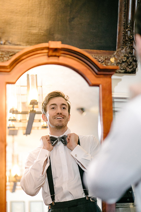 Groom in a light grey suit coat and black pants with a grey velvet bow tie