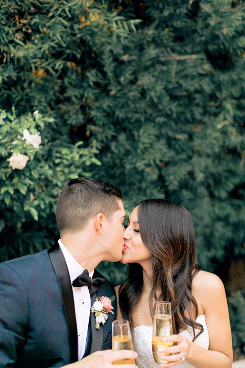 franciscan-gardens-wedding-bride-and-groom-kissing-bride-in-a-strapless-form-fitting-white-gown-groom-in-a-navy-shawl-lapel-tuxedo-with-black-accessories