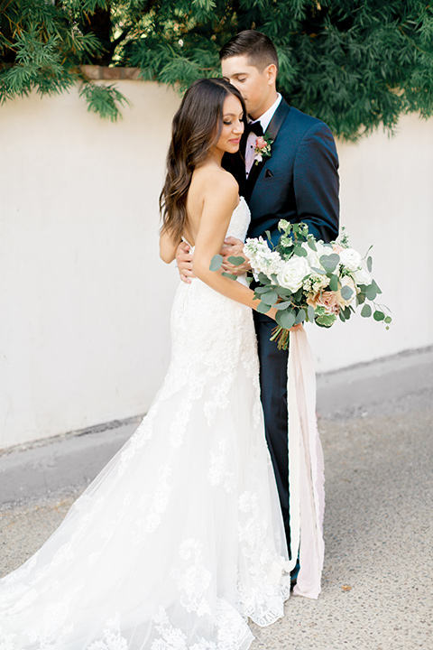 franciscan-gardens-wedding-bride-and-groom-standing-bride-in-a-strapless-form-fitting-white-gown-groom-in-a-navy-shawl-lapel-tuxedo-with-black-accessories