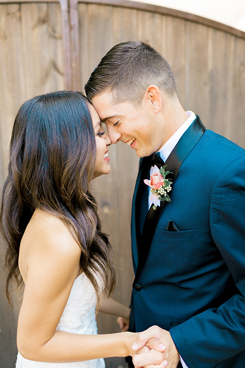 franciscan-gardens-wedding-bride-and-groom-touching-heads-bride-in-a-mermaid-white-strapless-gown-with-hair-down-in-a-simple-wave-and-groom-in-a-dark-blue-tuxedo-with-a-black-shawl-lapel-and-black-bow-tie