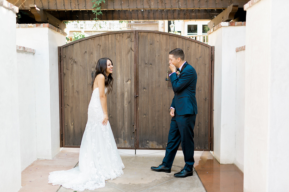 franciscan-gardens-wedding-first-look-bride-in-a-white-mermaid-strapless-gown-with-hair-down-and-simple-groom-in-a-navy-shawl-lapel-tuxedo-with-a-black-bow-tie