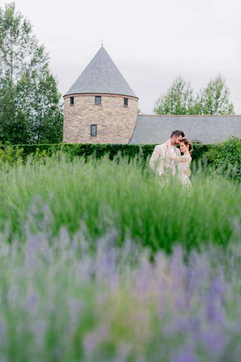 bride in a champagne and blush colored gown with the groom in a tan suit with a champagne bow tie by the lavender fields