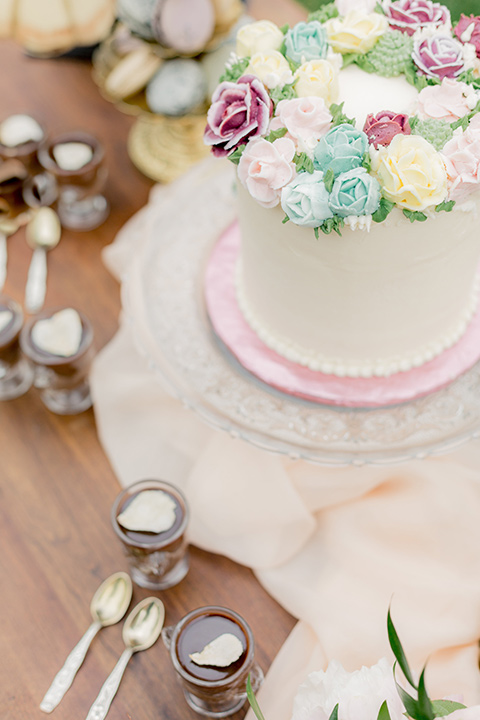 white cake with a rose colored trim and floral decor