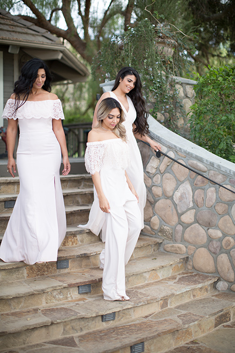 bride in a white jumpsuit and bridesmaids in pink gowns