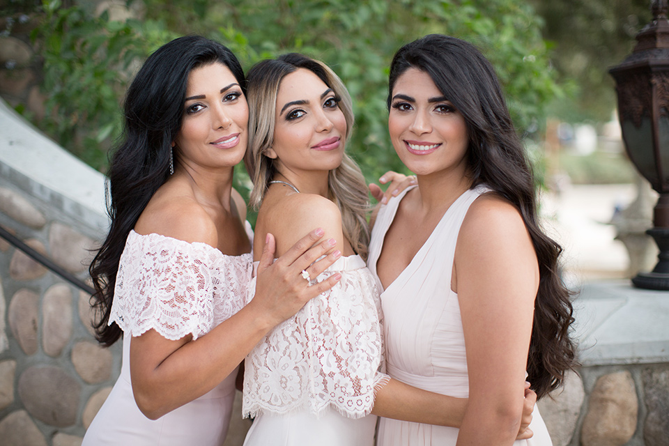 bride in a lace jumpsuit and bridesmaids in pink gowns