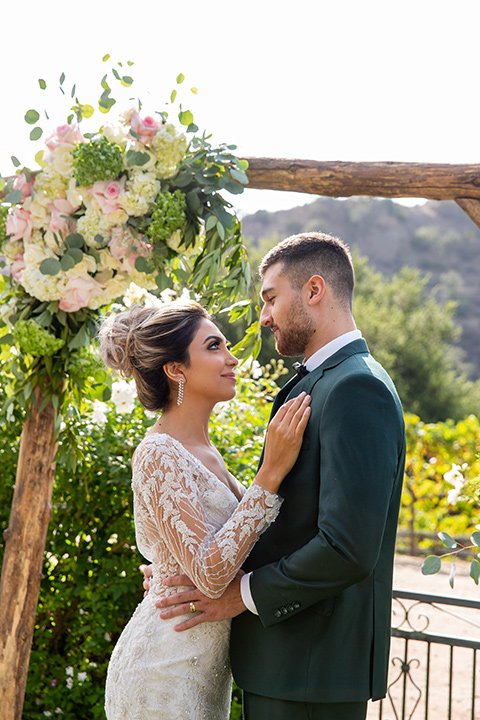 bride in a long sleeved gown with a satin underlay and hair up in a top knot bun groom in a dark green suit