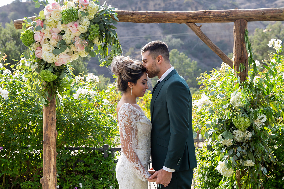 bride and groom at ceremony, groom in a dark green suit