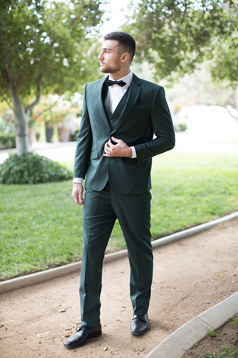  groom in a green suit with a black bow tie