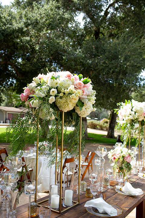  tall floral arrangements with candles on wooden tables