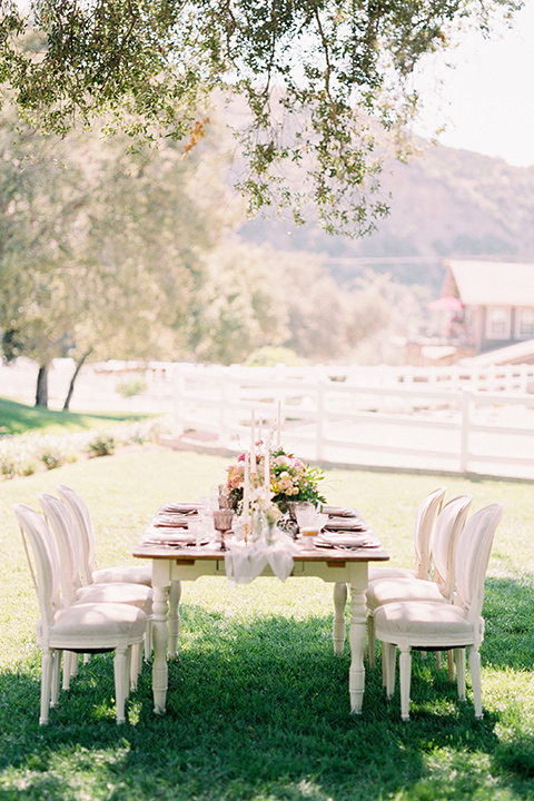 wooden table with wooden chairs and candles with florals and linens