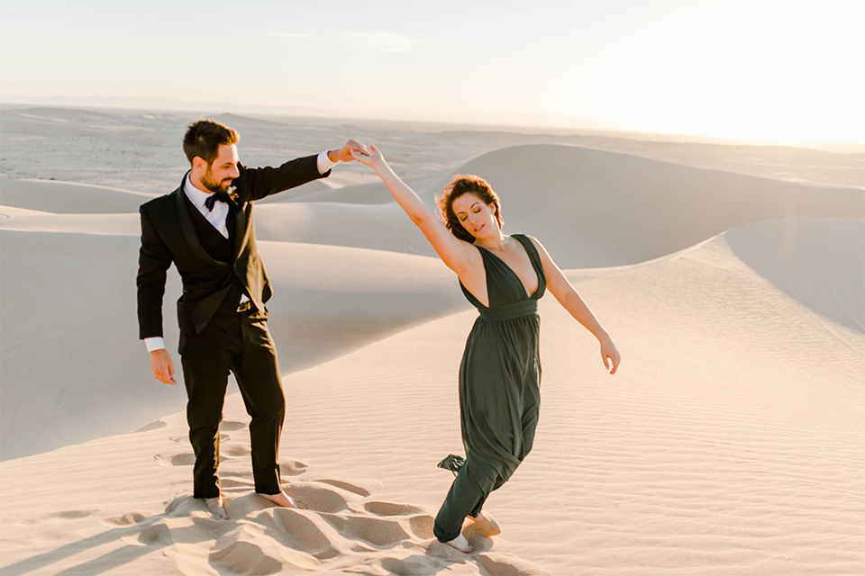 Glamis-Engagement-Shoot-bride-and-groom-dancing-bride-in-a-deep-green-flowing-dress-with-a-plunging-neckline-groom-in-a-black-tuxedo-with-navy-blue-velvet-bow-tie