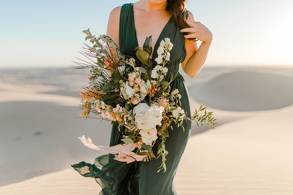 Glamis-Engagement-Shoot-close-up-on-bride-bride-in-a-deep-green-flowing-dress-with-a-plunging-neckline-groom-in-a-black-tuxedo-with-navy-blue-velvet-bow-tie