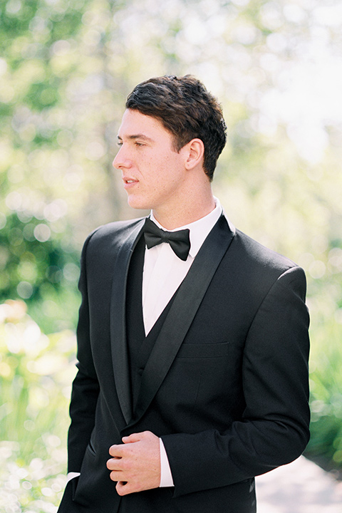  the groom in a black tuxedo and a black bow tie close up