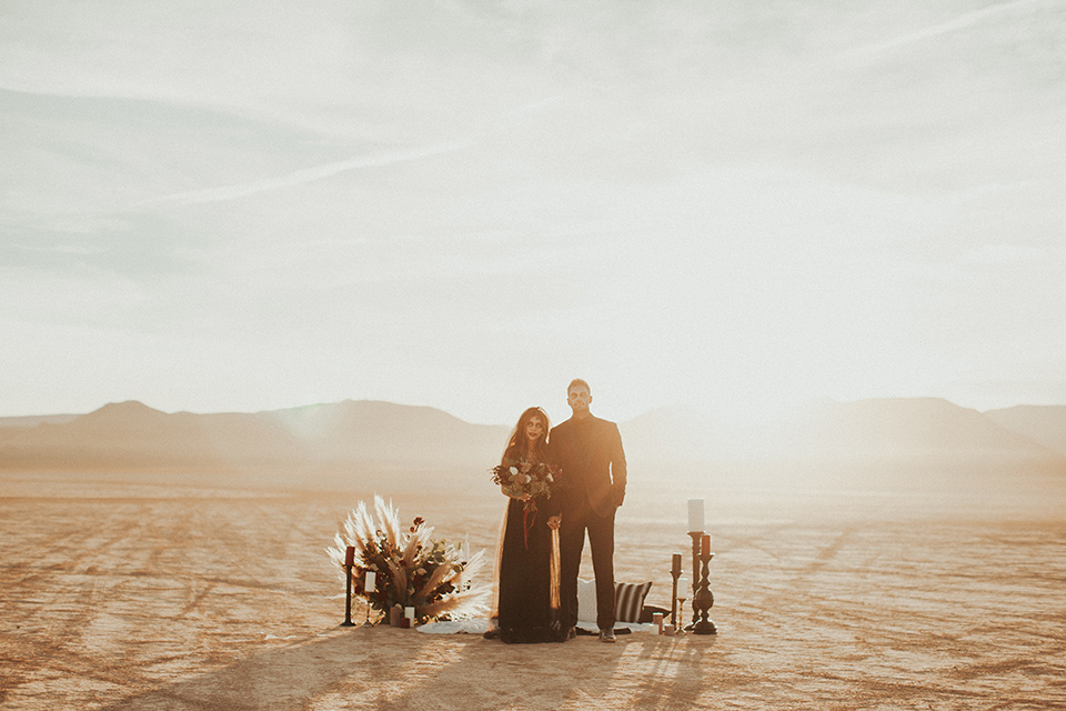 halloween shoot with the bride in a black and burgundy tulle gown with a black veil and skeleton makeup and the groom in a burgundy tuxedo with a black shirt and burgundy bow tie