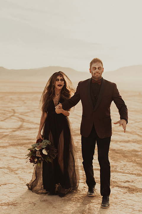 Halloween shoot with the bride in a skeleton makeup with a burgundy and black tulle gown and a black veil and the groom is in a burgundy tuxedo with a black shirt and burgundy bow tie