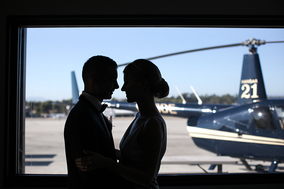 Bride and groom silhouettes with helicopter in background