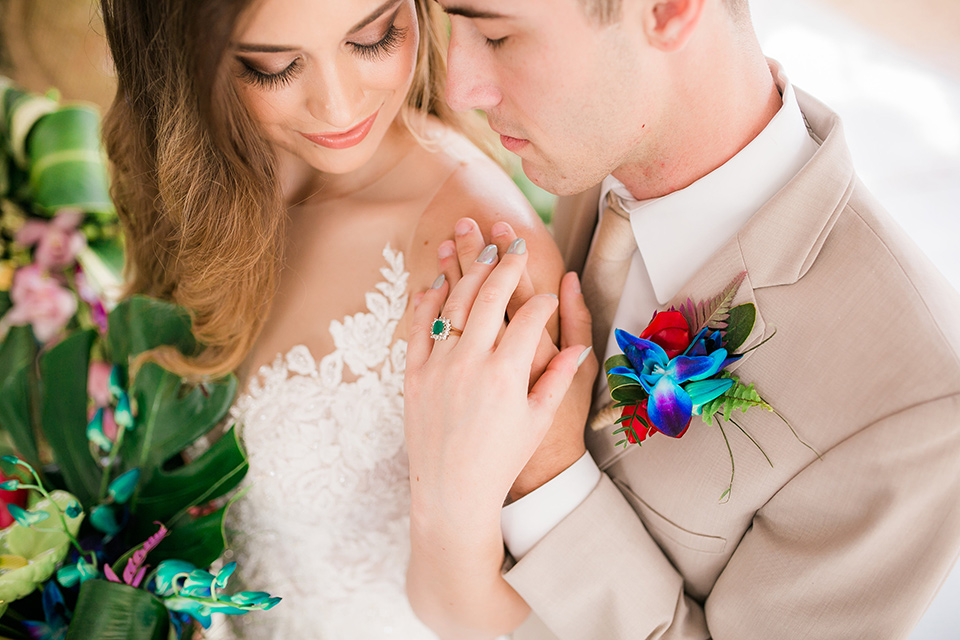 bride in a boho style gown with a bright colored floral crown and the groom in a tan suit with a tan long tie close up