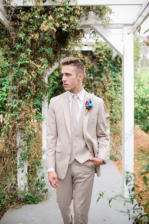 the groom in a tan suit with a tan long tie walking outside