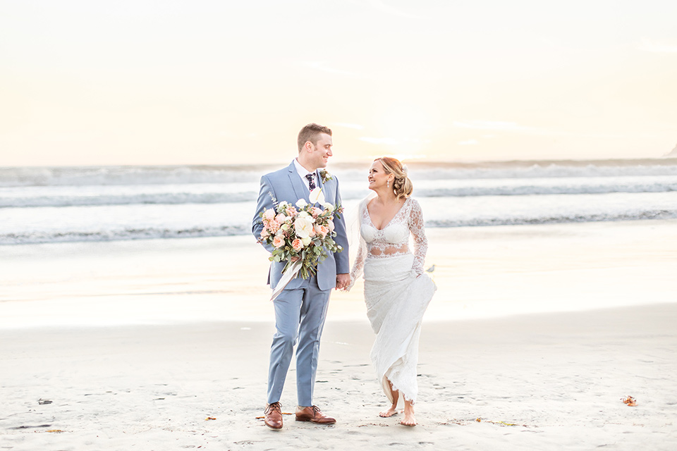 Bride and groom look each other in the eyes as they walk down the beach