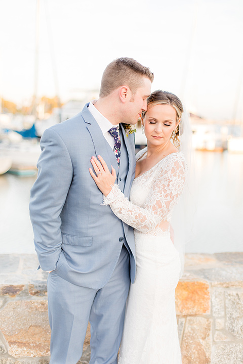 Bride and groom embrace each other in front of harbor