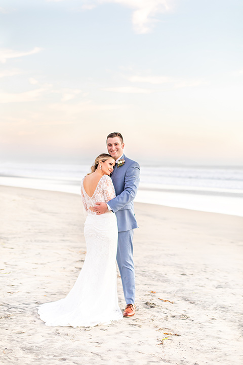 Bride and groom pose for a sunset beach wedding photo