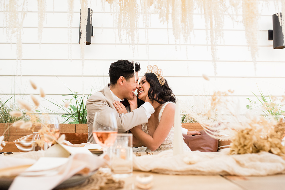  bride in a cream colored bohemian inspired gown with a gold crown, groom in a tan suit with a burgundy velvet bow tie 