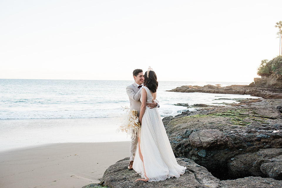  bride in a cream colored bohemian inspired gown with a gold crown, groom in a tan suit with a burgundy velvet bow tie 